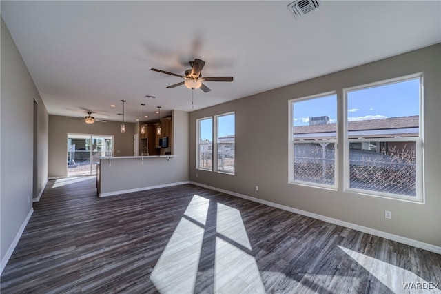 unfurnished living room featuring plenty of natural light, baseboards, visible vents, and dark wood finished floors