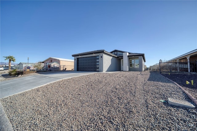 view of front of house featuring driveway, an attached garage, fence, and stucco siding