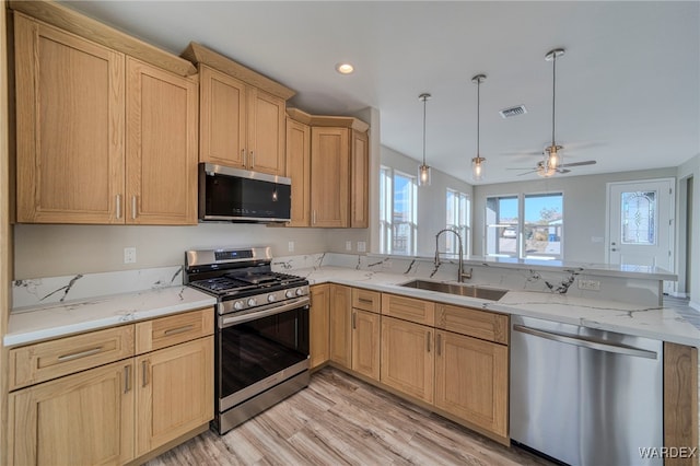 kitchen featuring stainless steel appliances, visible vents, hanging light fixtures, a sink, and a peninsula