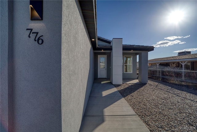 entrance to property with fence and stucco siding