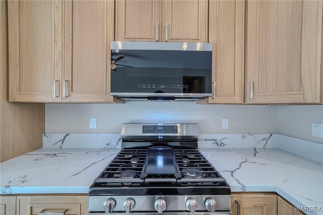 kitchen featuring appliances with stainless steel finishes, light brown cabinets, ceiling fan, and light stone countertops