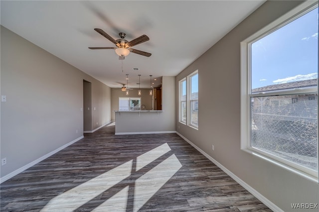 unfurnished living room with ceiling fan, visible vents, baseboards, and dark wood-type flooring