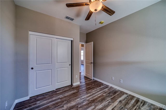 unfurnished bedroom with dark wood-style flooring, a closet, visible vents, and baseboards