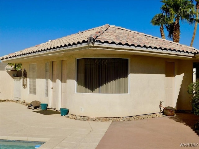 view of side of property featuring a patio area, a tiled roof, and stucco siding