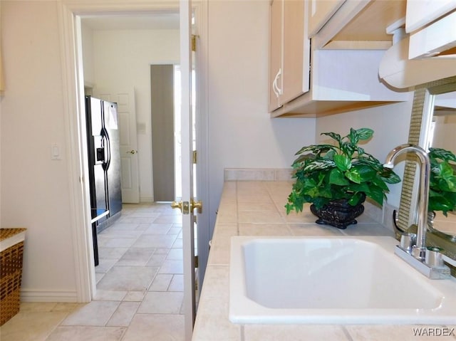 bathroom with tile patterned flooring, a sink, and baseboards