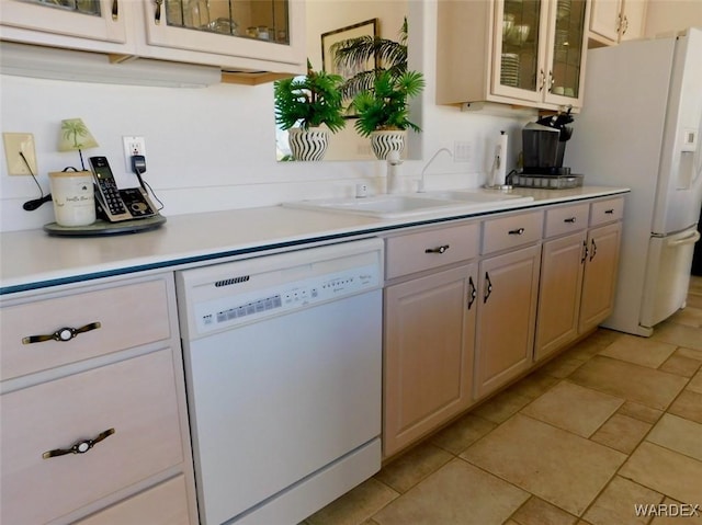 kitchen featuring glass insert cabinets, white appliances, light countertops, and a sink