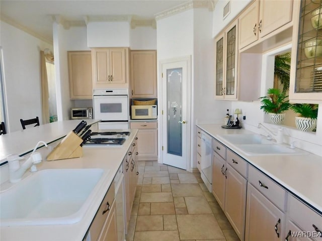 kitchen featuring white appliances, glass insert cabinets, a kitchen breakfast bar, light countertops, and a sink