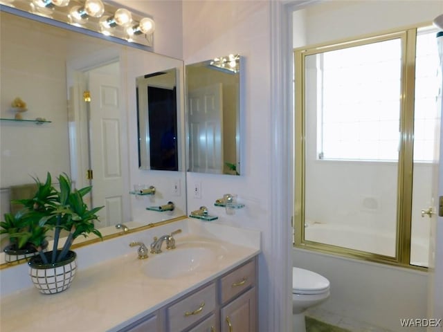 full bath featuring enclosed tub / shower combo, vanity, and toilet