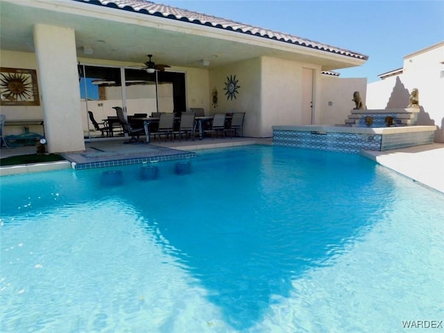 outdoor pool with ceiling fan, a patio, and a hot tub