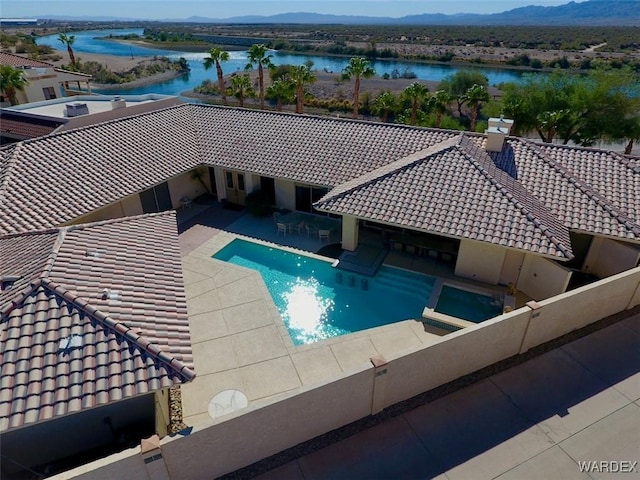 outdoor pool with a patio area and a water and mountain view