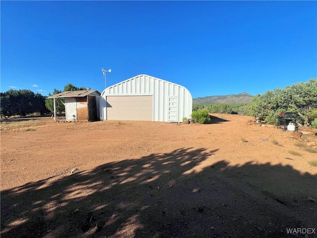 exterior space featuring a garage, driveway, an outdoor structure, and a mountain view