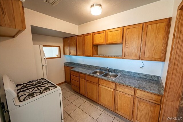 kitchen featuring white appliances, brown cabinetry, and a sink