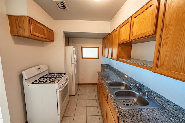 kitchen featuring white appliances, visible vents, dark countertops, brown cabinets, and a sink