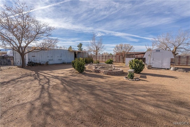 view of yard with a storage shed, an outdoor structure, and fence