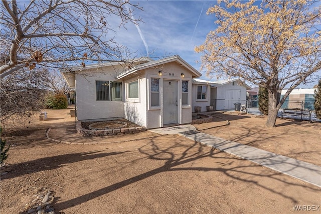 bungalow-style home with fence and stucco siding