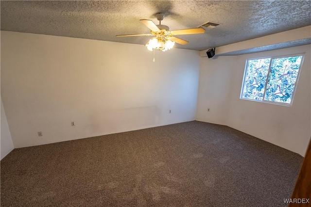 carpeted empty room with a ceiling fan, visible vents, and a textured ceiling