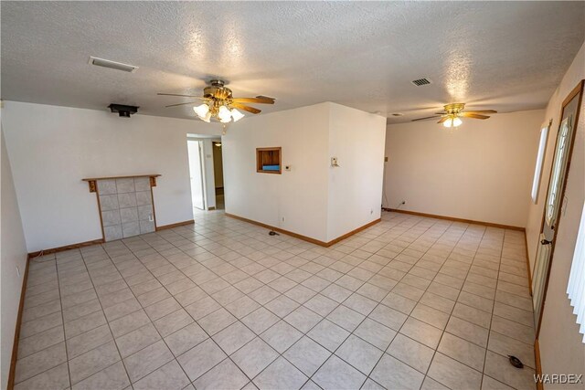 spare room featuring a ceiling fan, visible vents, a textured ceiling, and light tile patterned floors