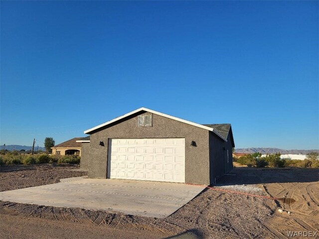 view of side of property featuring driveway, a garage, and stucco siding