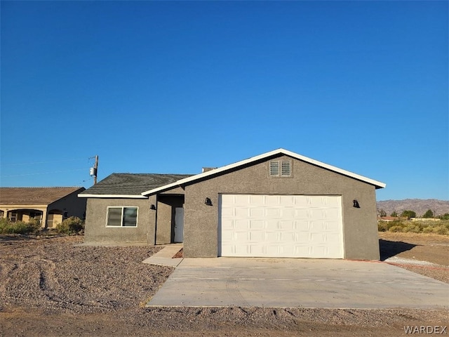 ranch-style home with concrete driveway, an attached garage, and stucco siding