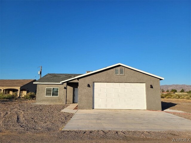 ranch-style home with concrete driveway, an attached garage, and stucco siding