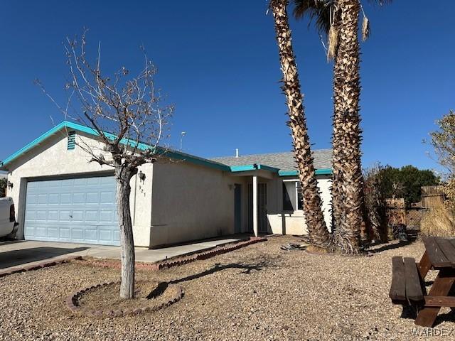 view of front of home with driveway, an attached garage, and stucco siding