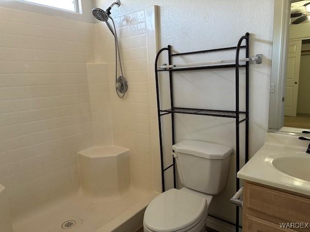 bathroom with a tile shower, vanity, and toilet