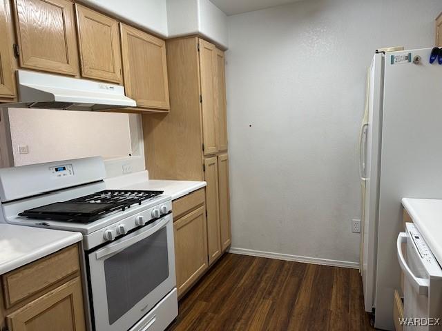 kitchen featuring white appliances, under cabinet range hood, light countertops, and dark wood finished floors