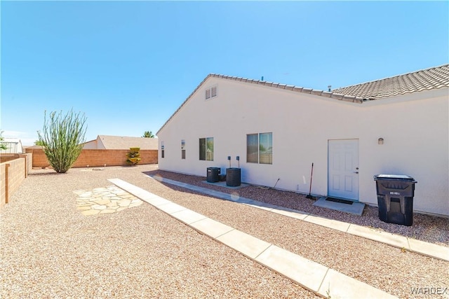 back of house with a tiled roof, a fenced backyard, and stucco siding