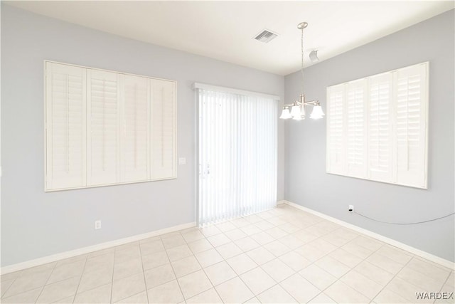 spare room featuring a chandelier, visible vents, and baseboards