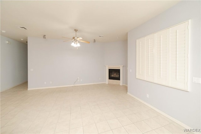 unfurnished living room with visible vents, baseboards, a ceiling fan, and a glass covered fireplace