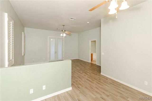 empty room with ceiling fan, light wood finished floors, visible vents, and baseboards