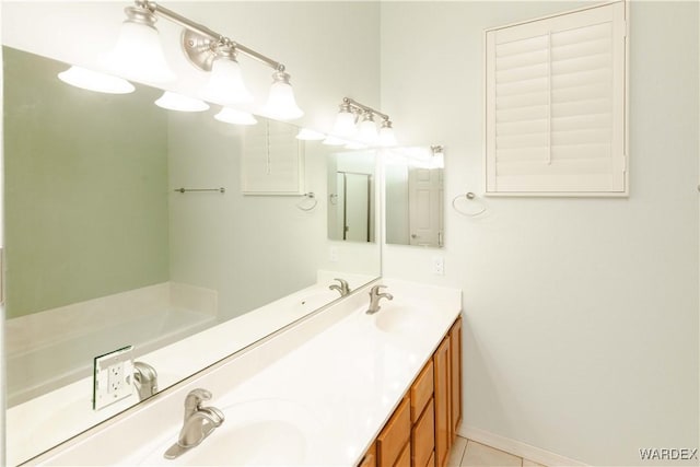 bathroom with baseboards, double vanity, a sink, and tile patterned floors