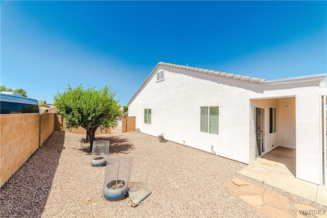 back of house with a patio area, a fenced backyard, and stucco siding