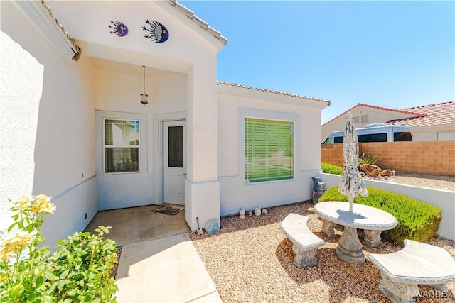 doorway to property featuring a patio area, fence, and stucco siding