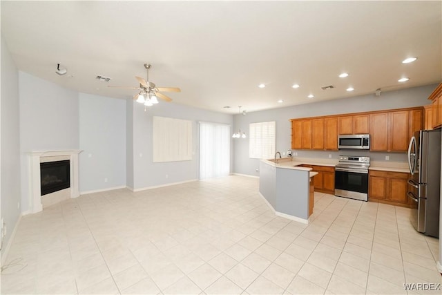 kitchen with visible vents, light countertops, appliances with stainless steel finishes, brown cabinetry, and open floor plan