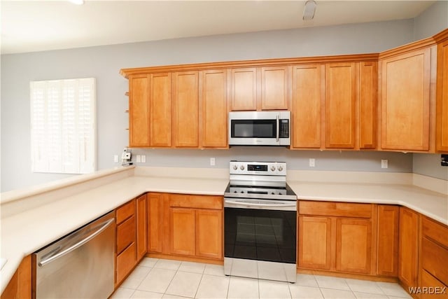 kitchen with light countertops, appliances with stainless steel finishes, and brown cabinetry