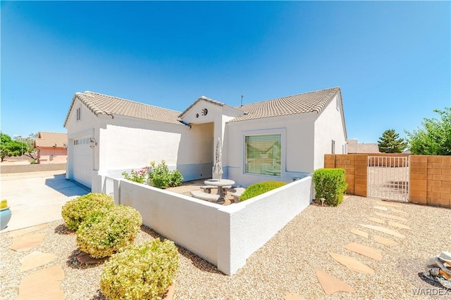 view of front of property featuring a garage, fence, a tiled roof, and stucco siding