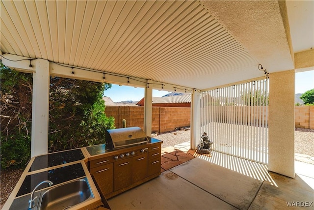 view of patio / terrace with a fenced backyard, an outdoor kitchen, a sink, and area for grilling