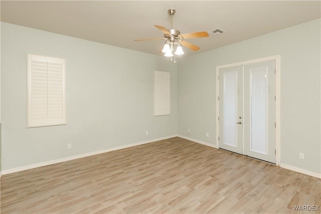 spare room with baseboards, visible vents, and light wood finished floors