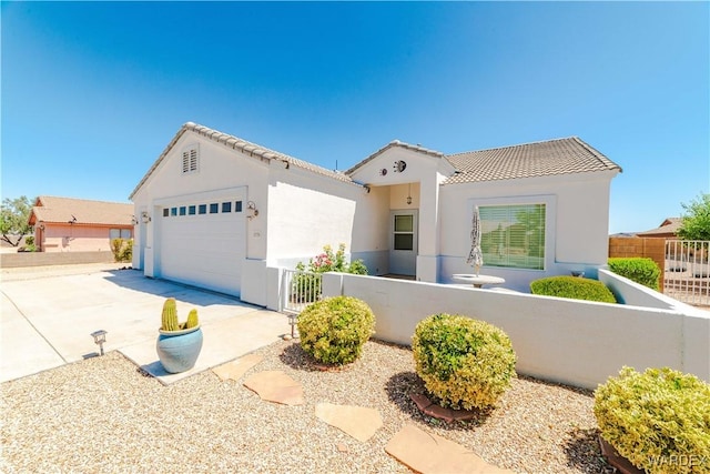 mediterranean / spanish-style home with a fenced front yard, stucco siding, concrete driveway, an attached garage, and a tiled roof