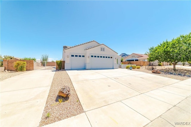 mediterranean / spanish house with a garage, concrete driveway, a tile roof, fence, and stucco siding