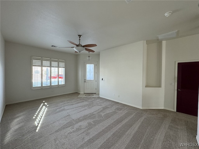 spare room with light carpet, ceiling fan, visible vents, and baseboards