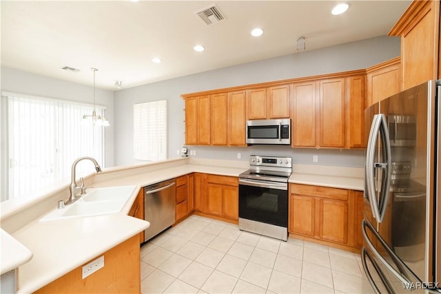 kitchen with stainless steel appliances, a sink, visible vents, light countertops, and pendant lighting