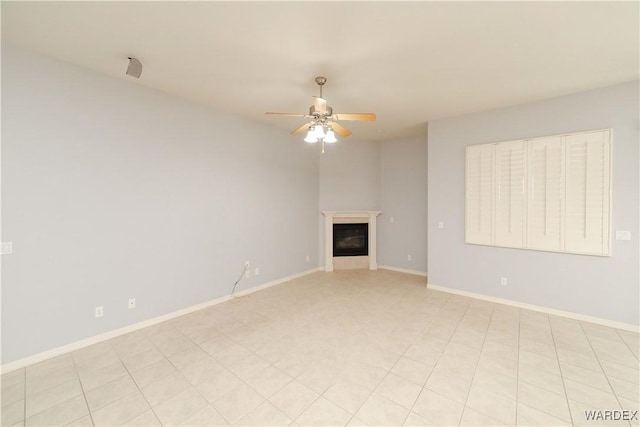 unfurnished living room featuring ceiling fan, baseboards, and a glass covered fireplace