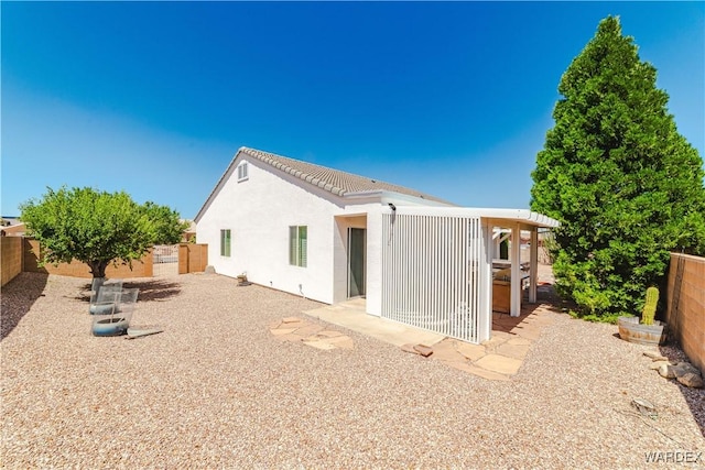 rear view of house featuring a tiled roof, a fenced backyard, and stucco siding