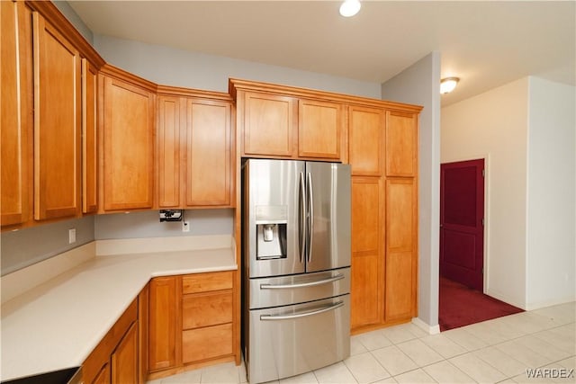 kitchen with brown cabinets, light countertops, stainless steel fridge, and light tile patterned flooring