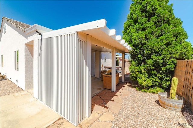 view of home's exterior with stucco siding, fence, and a patio