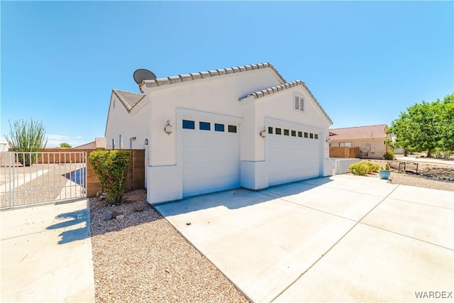 mediterranean / spanish-style house featuring an outbuilding, stucco siding, fence, a garage, and driveway