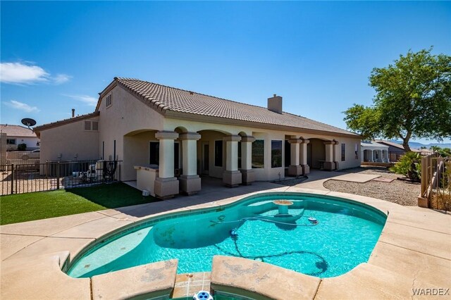 view of swimming pool with a patio area, a pool with connected hot tub, and fence