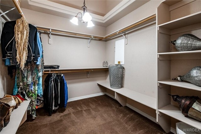 spacious closet featuring an inviting chandelier and dark carpet